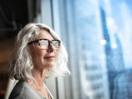 Woman smiling with glasses looking out window