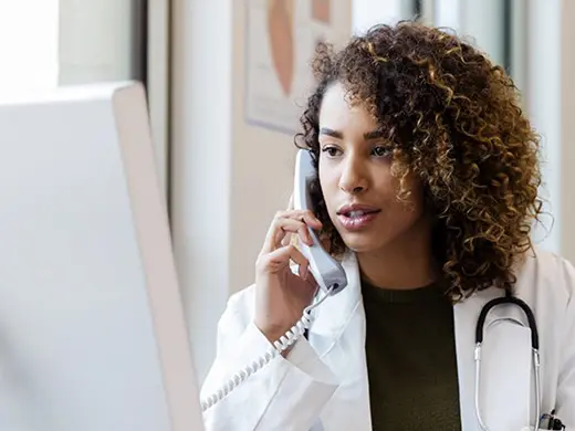 Médecin au téléphone regardant l'ordinateur