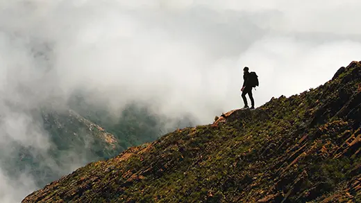 Hiker is looking at the cloudy mountains